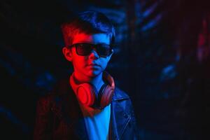 studio schot in donker studio met neon licht. portret van een elegant jongen met hoofdtelefoons foto