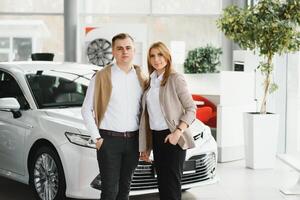 gelukkig jong paar kiest en buying een nieuw auto voor de familie in de handel foto