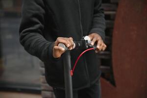 detailopname van Afrikaanse Amerikaans Mens Holding omgaan met van een zwart sta op scooter, wazig achtergrond foto