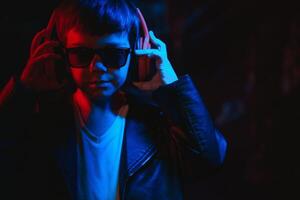 studio schot in donker studio met neon licht. portret van een elegant jongen met hoofdtelefoons foto