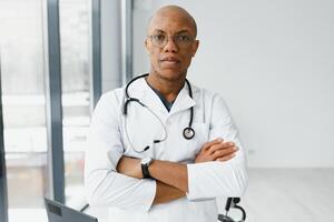 Afrikaanse Amerikaans Mens mannetje ziekenhuis dokter in wit jas met stethoscoop. foto