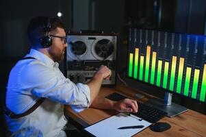 een mannetje spion luistert en records gesprekken Aan een reel-to-reel plakband opnemer foto