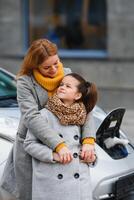 elegant moeder en dochter in rekening brengen een elektrisch auto, en besteden tijd samen foto