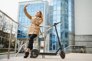 jong vrouw Aan elektro scooter in stad. vrouw rijden scooter in zonsondergang licht in straat foto