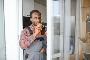 werkman in overall installeren of aanpassen plastic ramen in de leven kamer Bij huis foto