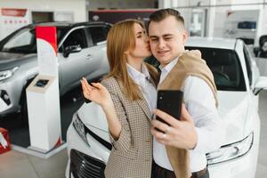 jong paar omzeilen een auto in een auto toonzaal. foto