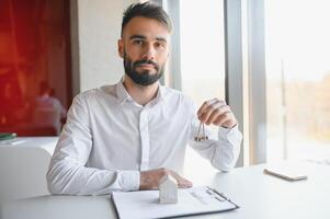 portret van een jong makelaar in de kantoor Bij de tafel. echt landgoed verkoop concept. foto