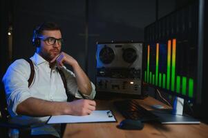 een mannetje spion luistert en records gesprekken Aan een reel-to-reel plakband opnemer foto