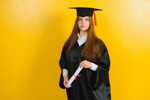 gelukkig aantrekkelijk afstuderen in een meester jurk, met een diploma Aan een geel achtergrond. concept van de diploma uitreiking ceremonie foto