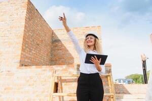 vrouw bouw ingenieur. architect met een tablet computer Bij een bouw plaats. jong vrouw op zoek, gebouw plaats plaats Aan achtergrond. bouw concept. foto