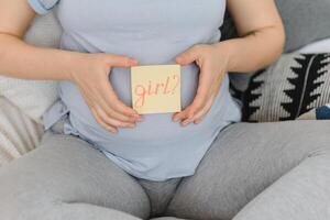zwanger vrouw in bed in de slaapkamer Holding een vraag kaart, jongen of meisje. foto