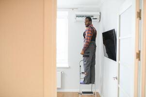 Afrikaanse Amerikaans elektricien repareren lucht conditioner binnenshuis foto