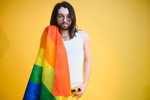 homo Mens houden regenboog gestreept vlag geïsoleerd Aan gekleurde achtergrond studio portret. mensen levensstijl mode lgbtq concept foto