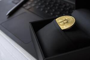 gouden bitcoin in zwart doos Aan de laptop toetsenbord. foto