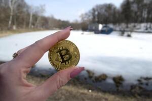 gouden bitcoin in vrouw hand. een munt van cryptogeld. foto
