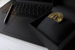 gouden bitcoin in zwart doos Aan de laptop toetsenbord. foto