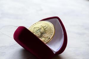 gouden bitcoin in rood doos. een munt van cryptogeld. foto