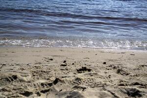 nat zand en zacht golven Aan een strand. foto