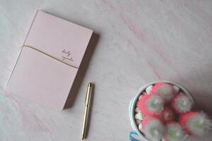 notitieboekje en pen Aan de roze getextureerde achtergrond. foto
