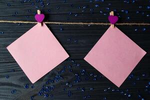roze memo lakens vastgemaakt met een decoratief pin Aan een donker blauw houten bord. foto