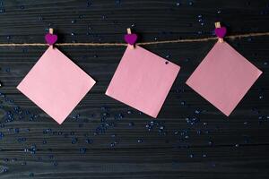 roze memo lakens vastgemaakt met een decoratief pin Aan een donker blauw houten bord. foto