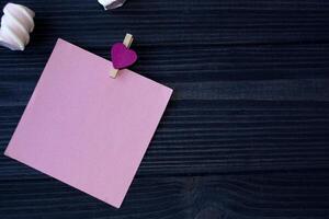 de vel van roze papier, pen en heemst Aan een donker blauw houten tafel. foto