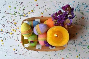 kleurrijk Pasen eieren met bloemen en geel kaars in de mand. mooi Pasen achtergrond. Pasen kaart. eigengemaakt vakantie decor. foto