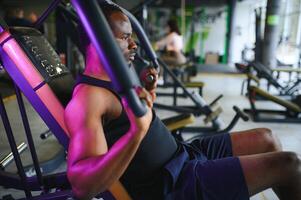 gemotiveerd jong zwart sportman hebben training Aan roeien machine foto