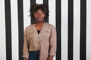 mooi vrouwelijk portret op de zwarte en blauwe strepen type achtergrond. Afro-Amerikaans meisje trekt geschokt gezicht