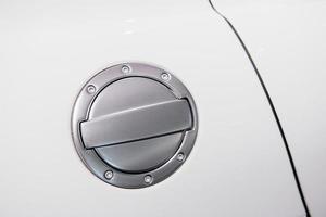 close-up shot van chromen brandstoftankdeksel of gasvuldop van witte sportwagen met ronde metalen brede bekleding met zeshoekige schroeven foto