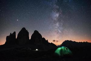 twee verlichtingstenten met toeristen binnen in de buurt van de tre cime drie pieken bergen 's nachts foto