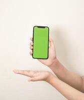 hand- is Holding een telefoon met groen scherm Aan een wit geïsoleerd achtergrond foto
