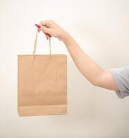 hand- Holding een boodschappen doen papier zak tegen een wit geïsoleerd achtergrond foto