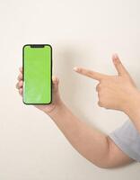 hand- is Holding een telefoon met groen scherm Aan een wit geïsoleerd achtergrond foto