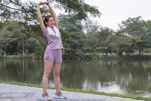 jong Aziatisch vrouw duurt zorg van haar Gezondheid door oefenen. rekken uw poten in de park foto