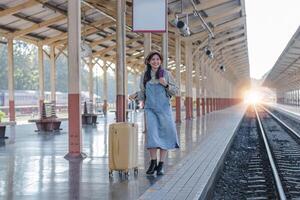 jong Aziatisch vrouw in modern trein station vrouw backpacker passagier aan het wachten voor trein Bij trein station naar Gaan Aan vakantie. foto