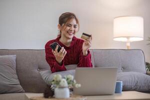 vrouw Holding credit kaart en gebruik makend van smartphone Bij huis, online winkelen, online bankieren, betaling, uitgeven geld, e-commerce Bij op te slaan, credit kaart concept foto