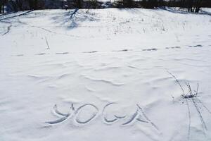 yoga brieven zijn geschreven Aan de sneeuw in winter in de verkoudheid seizoen. stilte in de tekst van yoga symbolen, een zonnig dag. foto