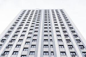 modern woon- complex met veel appartementen. de gebouw stijgt hoog in de lucht. perspectief en streng lijnen. facade van een appartement gebouw foto