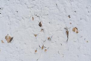 een oud wit muur met scheuren gips. de gebarsten oppervlakte van de muur. getextureerde oppervlak. vernieuwing verplicht foto