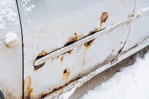 sporen van Roest Aan een wit auto. corrosie van de auto lichaam verwoesting van metaal onderdelen van de auto lichaam. foto