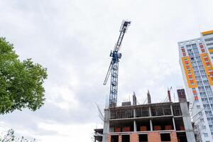 bouw van een hoogbouw meerdere verdiepingen gebouw, een hoogbouw kraan, een steen muur, een woon- hoogbouw gebouw, de facade van de huis. foto