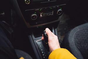 de Mens schakelaars de versnellingsbak Aan de automatisch. een auto met een automatisch overdragen. snelheid controle systeem foto