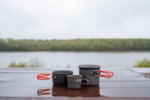 een reeks van toerist borden, drie items voor aan het eten een pot met handvatten, metaal gerechten staan Aan een tafel in natuur, een nat tafel, regenachtig het weer. foto