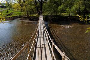 houten brug aan de overkant de rivier, panorama, landschap Aan de rivier, scharnierend kruispunt. Ondiep rivier. zonnig dag, lente, zomer. foto