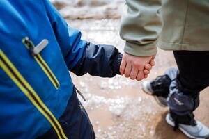 de kind houdt zijn moeder hand- wandelen in natuur, handen detailopname, stevig Holding handen, familie wandelen. foto