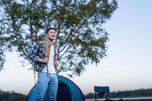 Mens Aziatisch op reis met tent camping Aan berg top buitenshuis avontuur levensstijl wandelen actief zomer vakanties foto