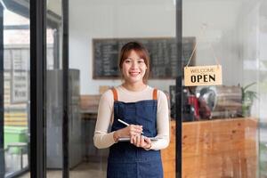 geslaagd klein bedrijf eigenaar jong Aziatisch vrouw barista staan Bij haar cafe foto