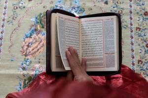 hand- van een moslim vrouw Holding de koran met Indonesisch vertaling foto