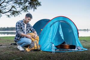 Mens Aziatisch op reis met tent camping Aan berg top buitenshuis avontuur levensstijl wandelen actief zomer vakanties foto